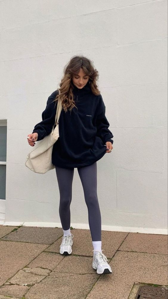a sport chic outfit with a black zip sweatshirt, grey leggings, white socks and trainers, a neutral oversized tote for spring