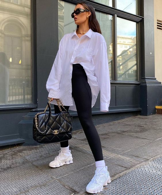 a very simple sport chic look with an oversized white shirt, black leggings, white trainers and socks, a black quilted bag