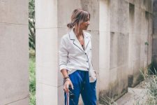 a creative look with a black and white pjama-style shirt, blue joggers, heels and layered bracelets is cool