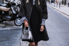 With black dress, striped bell sleeved shirt, dark gray three quarter sleeved coat, rounded sunglasses and black leather embellished flat boots