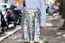 With light blue button down long sleeved shirt, silver knee-length skirt, sunglasses and hot pink clutch
