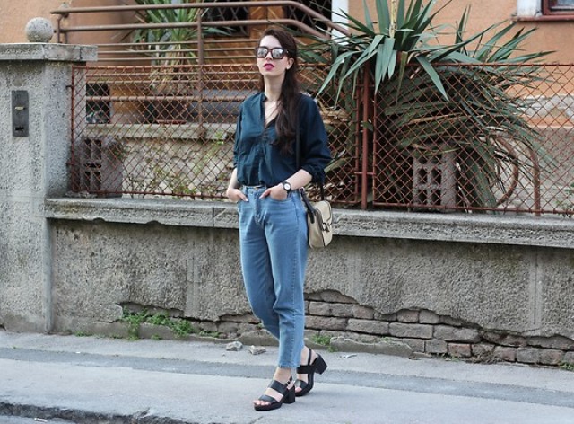 With navy blue button down shirt, loose jeans, beige and black bag and black leather sandals