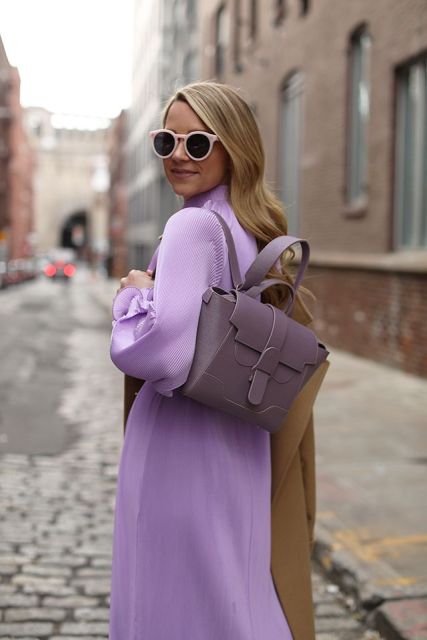 With pale pink framed sunglasses, lilac ruffled midi dress and brown midi coat