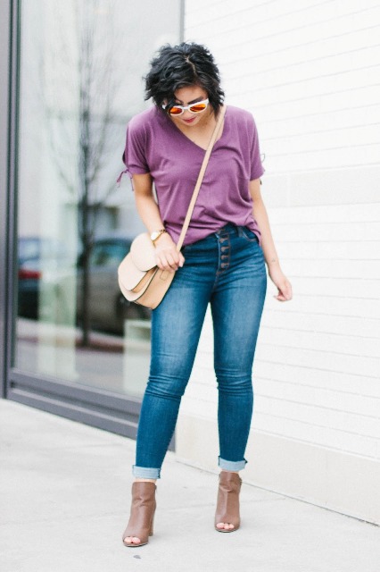 With purple loose t-shirt, beige crossbody bag, cuffed skinny jeans and light brown cutout ankle boots
