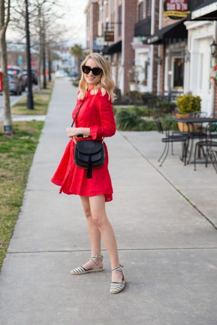 With red belted asymmetrical dress, oversized sunglasses and black tassel crossbody bag