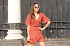 With red wrap ruffled bell sleeved mini dress, white framed sunglasses and brown leather fishnet bag