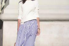 With white loose sweatshirt, beige framed oversized sunglasses, white and navy blue striped button front knee-length skirt and white and brown bag