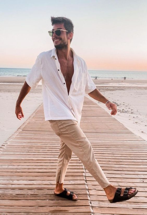 a beach outfit with a white linen oversized shirt with black buttons, tan pants, black slippers always works