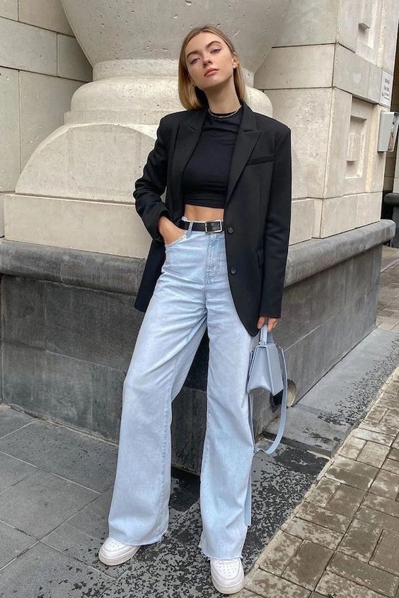 a black crop top, an oversized black blazer, light blue high waisted jeans, white sneakers and a light blue bag