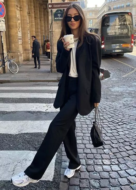 a black pantsuit with an oversized blazer, a white t-shirt, a chain necklace, white trainers and a black bag