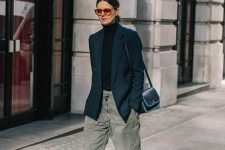 a black turtleneck, an oversized black blazer, grey baggy jeans, white trainers and socks and a black bag for a comfy spring look
