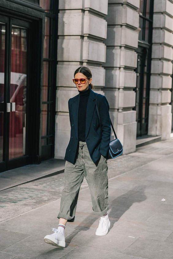 a black turtleneck, an oversized black blazer, grey baggy jeans, white trainers and socks and a black bag for a comfy spring look