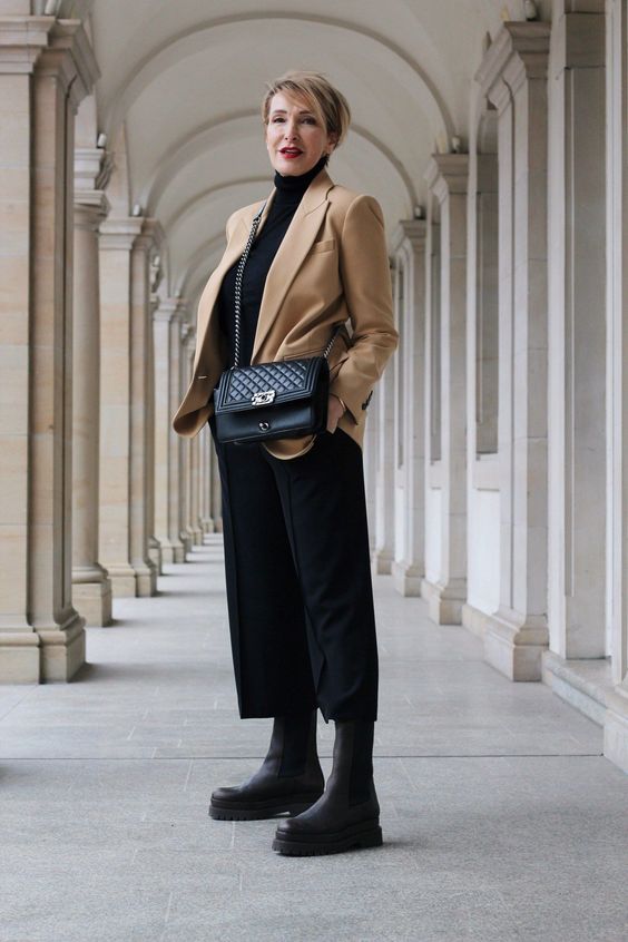 a bold and contrasting look with a black turtleneck, culottes, chunky boots, a bag and a beige blazer is amazing