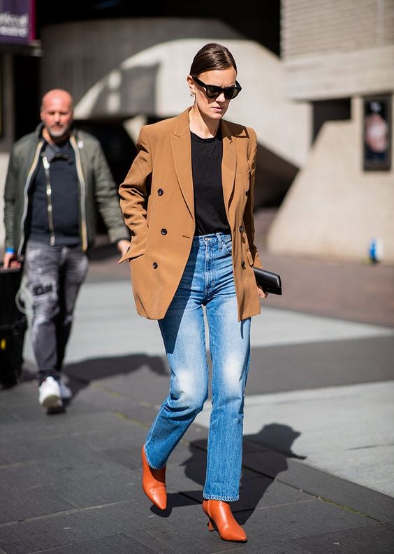 a bright and chic look with a black t shirt, blue jeans, red boots, a camel blazer and a small black clutch for spring