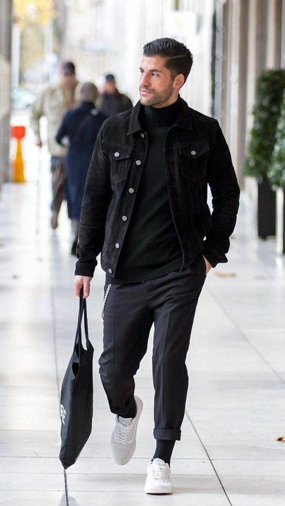 a casual outfit with a black turtleneck, a denim jacket, grey pants, black socks, white sneakers and a black tote
