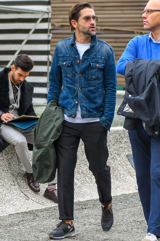 a casual outfit with a white t-shirt, a blue cropped denim jacket, black trousers, black trainers and an army jacket