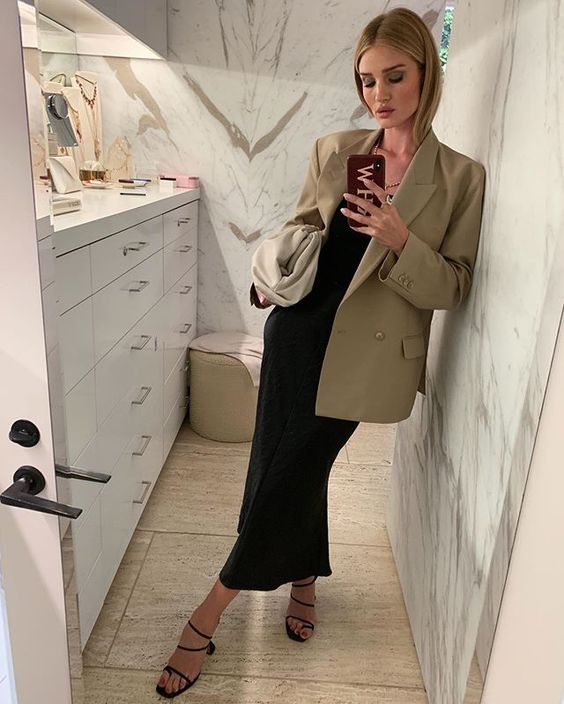 a chic and elegant office look with a black slip midi dress, black strappy heels, an oversized beige blazer, a neutral clutch