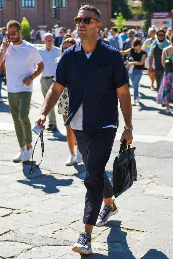 a suitable for work contrasting look with a white t-shirt, a navy short-sleeved shirt, navy pants, colorful trainers, a black leather bag