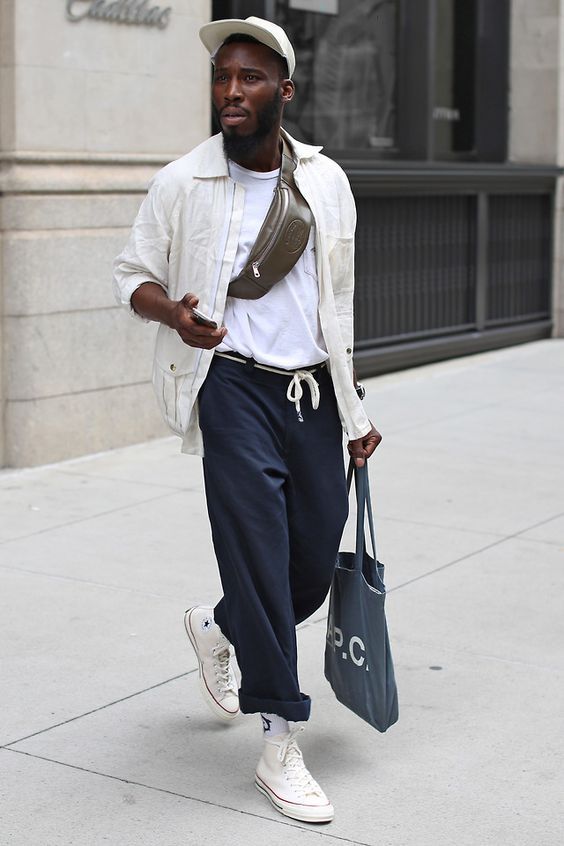 a contrasting outfit with a white t-shirt, a creamy jacket, navy trousers with a white rop, white sneakers and socks, a waistbag and a tote