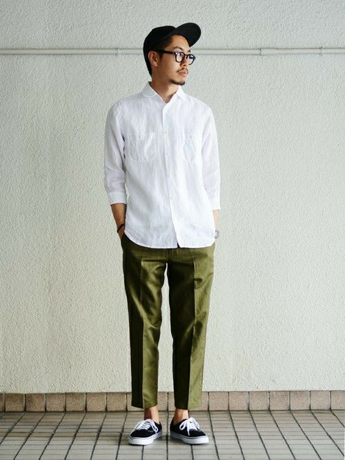 a minimal summer outfit with a white linen shirt, green cropped trousers, black sneakers and a black cap
