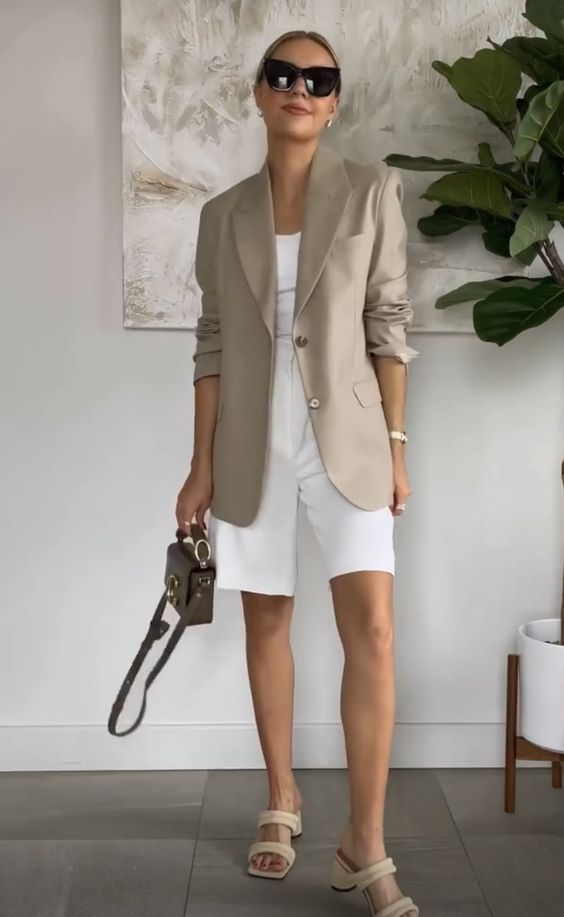 a pretty office look for spring or summer, with a white top, white Bermuda shorts, an oversized beige blazer, nude heels and a taupe bag