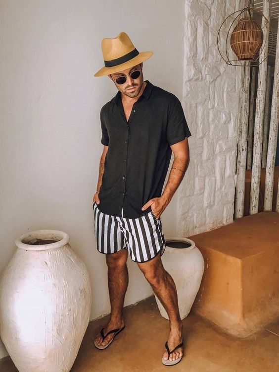 a relaxed monochromatic summer look with a black short sleeved shirt, black and white striped shorts, black flipflops and a hat