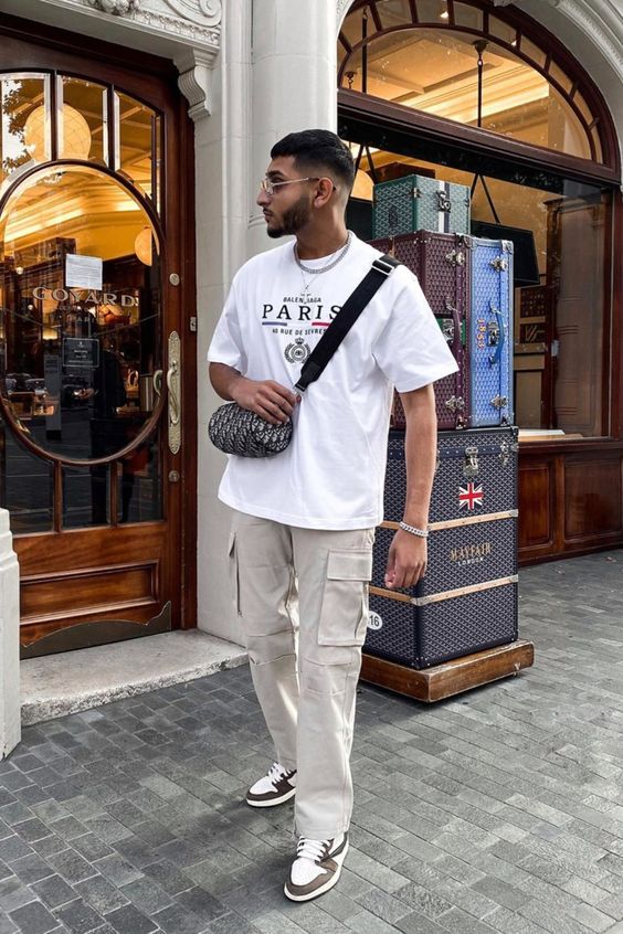 a relaxed outfit with a white printed t-shirt, grey cargo pants, black and white trainers and a printed bag