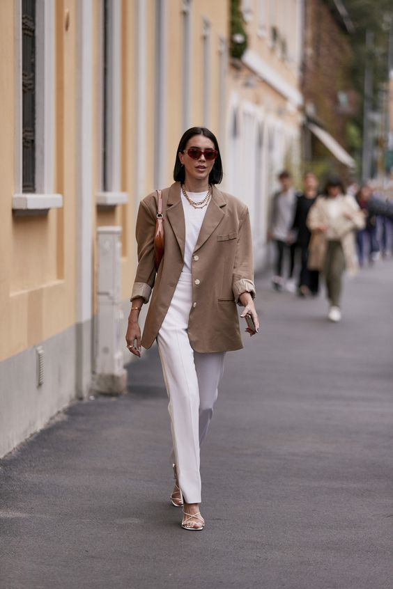 a stylish and elegant outfit with a white t-shirt, trousers, white strappy heels and a brown bag