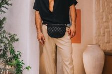 a summer or vacation look with a black short-sleeved shirt, tan cuffed pants, black slippers and a black waist bag is easy and cool