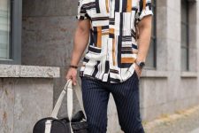 a summer outfit with a printed short-sleeved shirt, black thin stripe pants, a catchy bag and beige birkenstocks