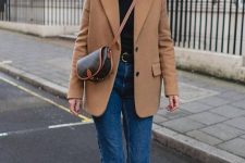 a timeless outfit with a black turtleneck, blue cropped jeans, brown boots, a camel blazer and a chic saddle bag