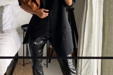 a total black look with a top, leather pants, an oversized black blazer, black sandals and a brown clutch