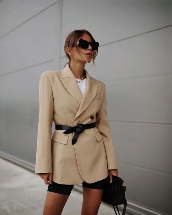 a trendy summer look with a white t shirt, black biker shoes, an oversized beige blazer, a black belt and a black bag is wow