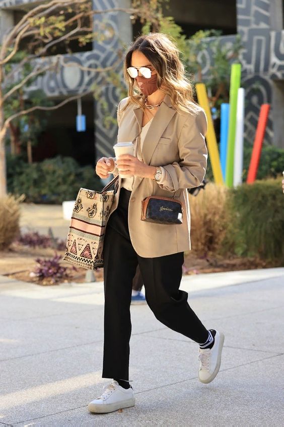 a whiet top, a tan oversized blazer, pants, black and white socks and white sneakers plus a small bag