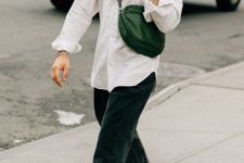a white button down, black jeans, black loafers, a green waist bag and a green baseball cap