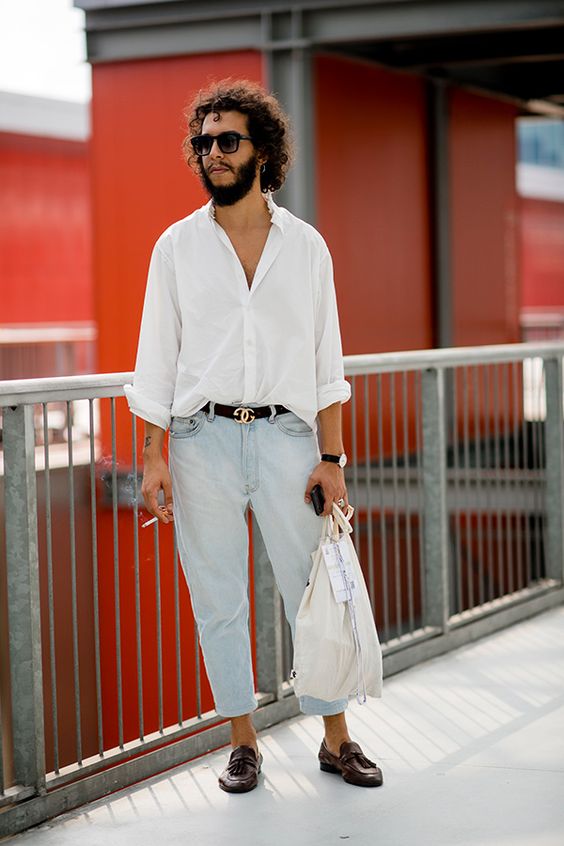 a white oversized button down, bleached blue jeans, a black belt and brown loafers plus a neutral tote