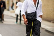 a white oversized linen button down, black thin stripe wideleg pants, white sneakers, a black bag and a yellow belt