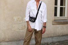 a white shirt with pockets and a logo, beige pants, white trainers and a black bag for an everyday look in spring or summer