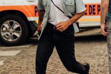 a white t-shirt, a mint blue short sleeve shirt with pockets, black jeans, black trainers, a black crossbody bag