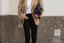 a white t-shirt, black cropped jeans, black strappy heels, an oversized beige blazer and a black woven clutch and cat-eye sunglasses