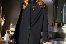 an elegant total black outfit with a turtleneck, black leather pants, an oversized black blazer with pockets and layered necklaces