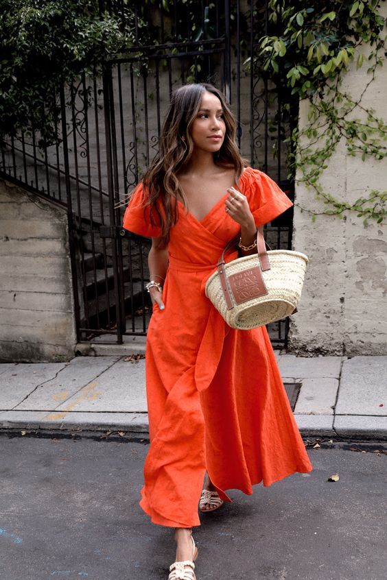 a bold orange midi dress with a deep neckline, wide sleeves and a sash will make a statement, neutral shoes and a straw bag are great additions here