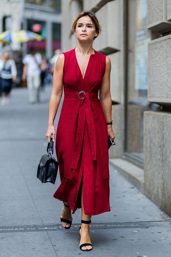 a deep red A line sleeveless midi dress with a sash and a a cool buckle, black ankle strap heels and a black bag