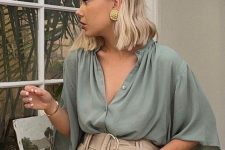 12 a casual summer look with an olive green shirt with wide sleeves, high waisted tan shorts with pockets and statement earrings