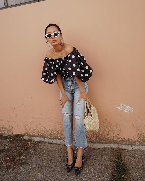 a summer party look with a black polka dot off the shoulder top, blue cropped jeans, black shoes and a straw bag plus statement earrings