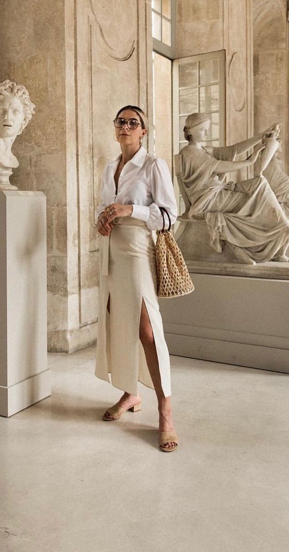 an elegant neutral look with a white button down, a tan midi skirt with two slits and a sash, nude mules and a bag
