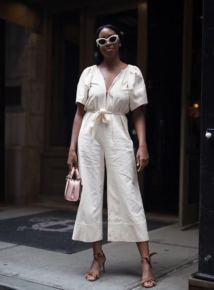 a beautiful and romantic work look with a creamy linen jumpsuit, short sleeves and flare pants, brown tie up shoes and a blush bag