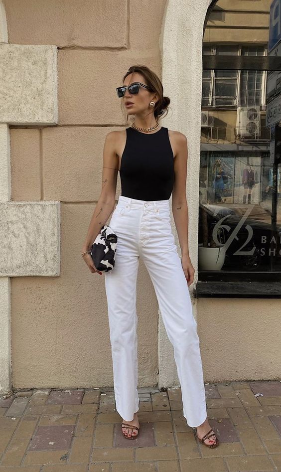 a black halter neckline top, white high waisted jeans, black strappy shoes, a chunky chain necklace and statement earrings