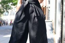 21 a black sleeveless cropped jumpsuit with wideleg pants, pockets and a sash, a printed hat and red block heels is amazing
