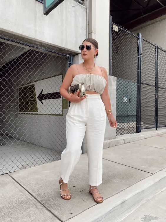 a pretty and neutral summer brunch outfit with a grey crop top, white high waisted pants, embellished sandals and a metallic bag